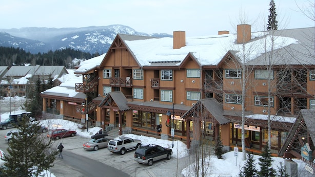 A lodge with multiple floors, a ski lift, and a view of snow-covered mountains.