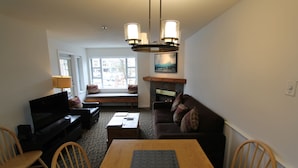 A living room with a TV, sofa, dining table, chairs, and a fireplace.