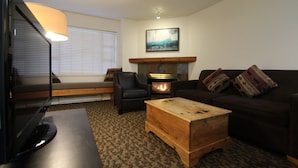 A cozy living room with a fireplace, a sofa, a chair, and a coffee table.