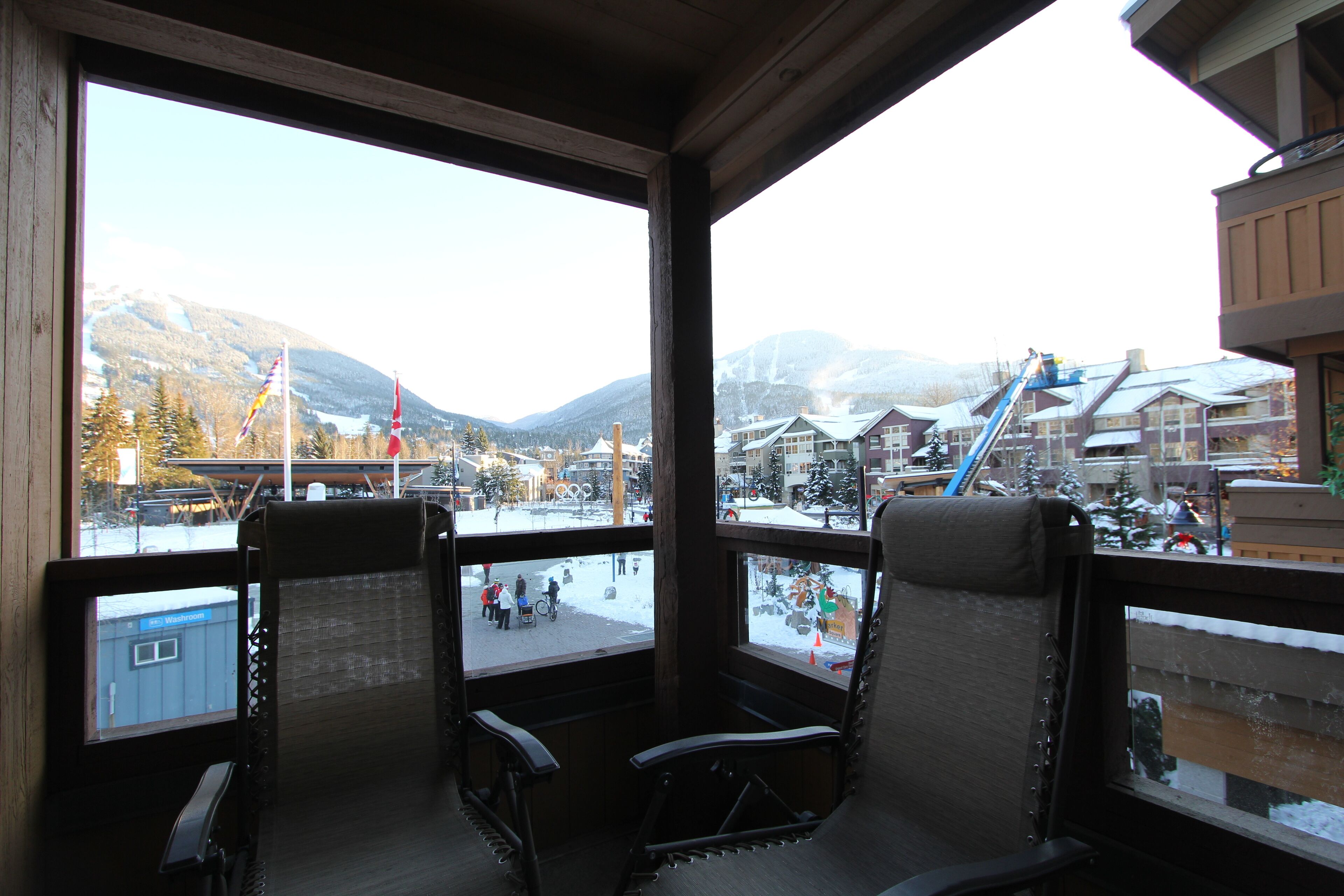 A room with a view of a snowy mountain area, including a ski lift and buildings.