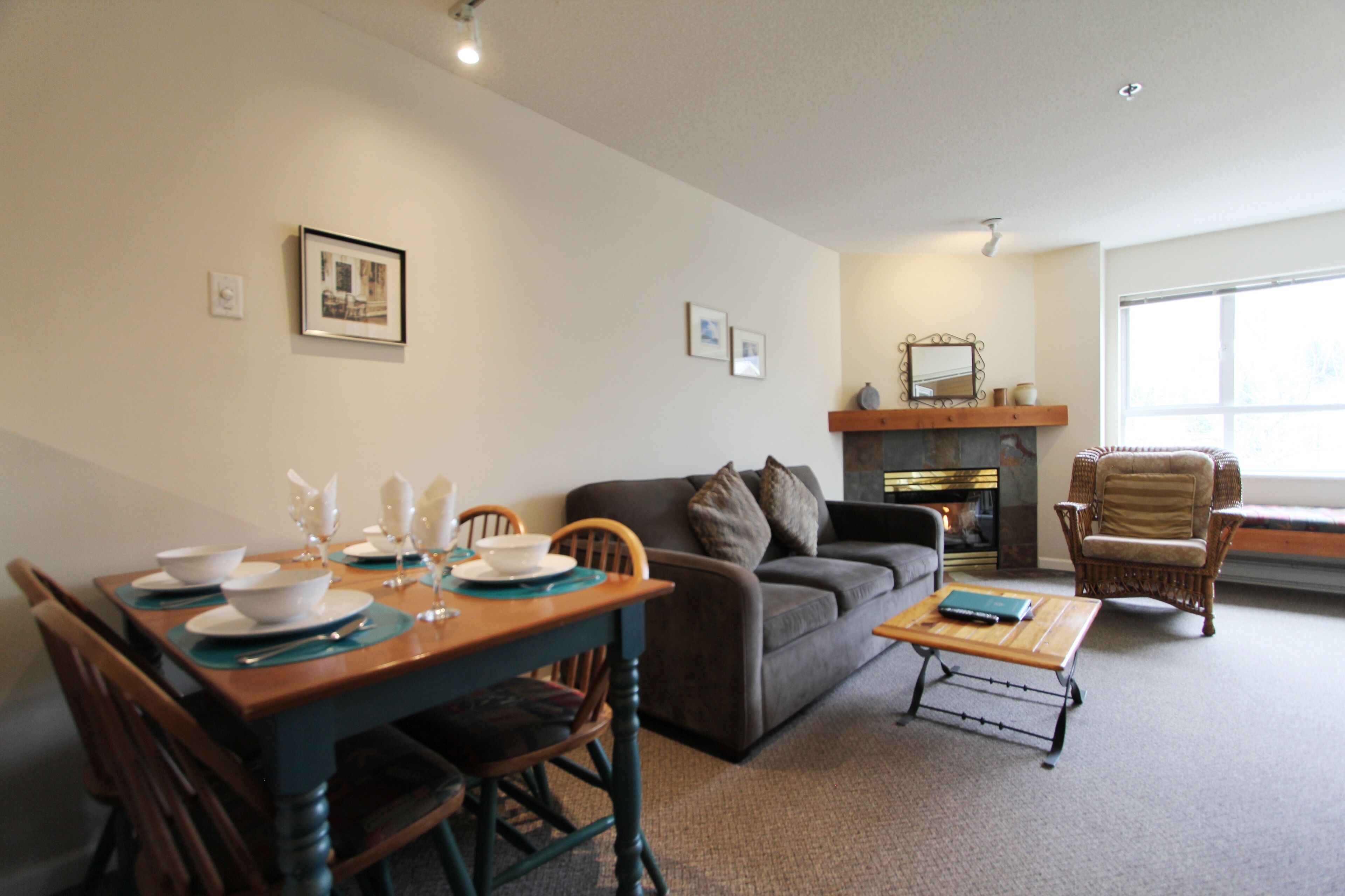A living room with a dining table set for four, a sofa, a coffee table, and a fireplace.