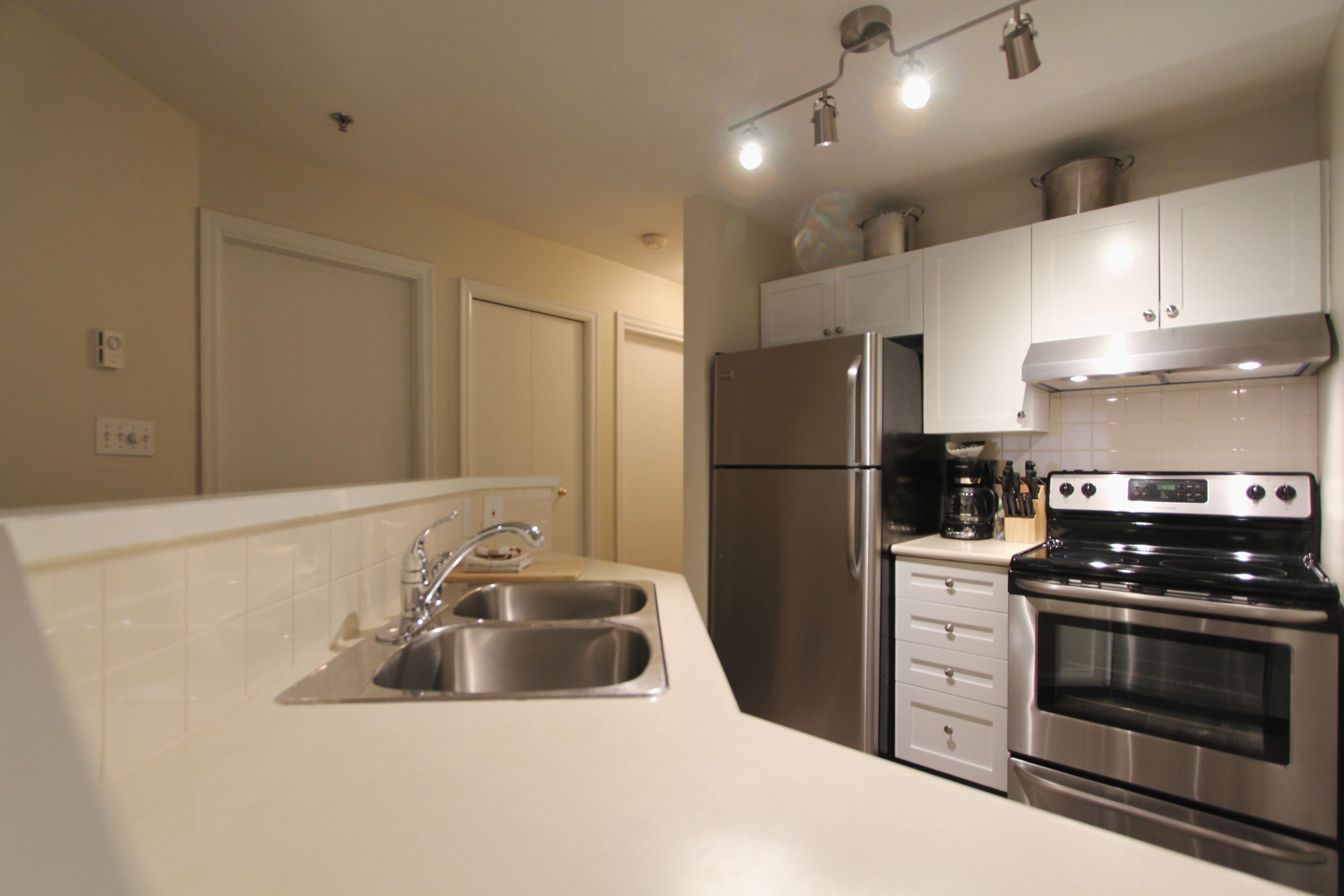 A modern kitchen with stainless steel appliances, a double sink, and white cabinetry.