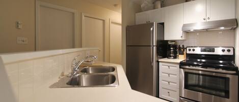 A modern kitchen with stainless steel appliances, a double sink, and white cabinetry.