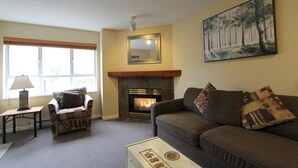 A living room with a fireplace, a sofa, a chair, and a painting on the wall.