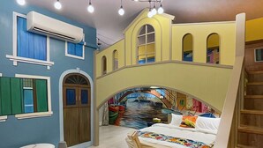 Una habitación con una cama, una mesita y un mural en la pared que muestra un puente y barcos.