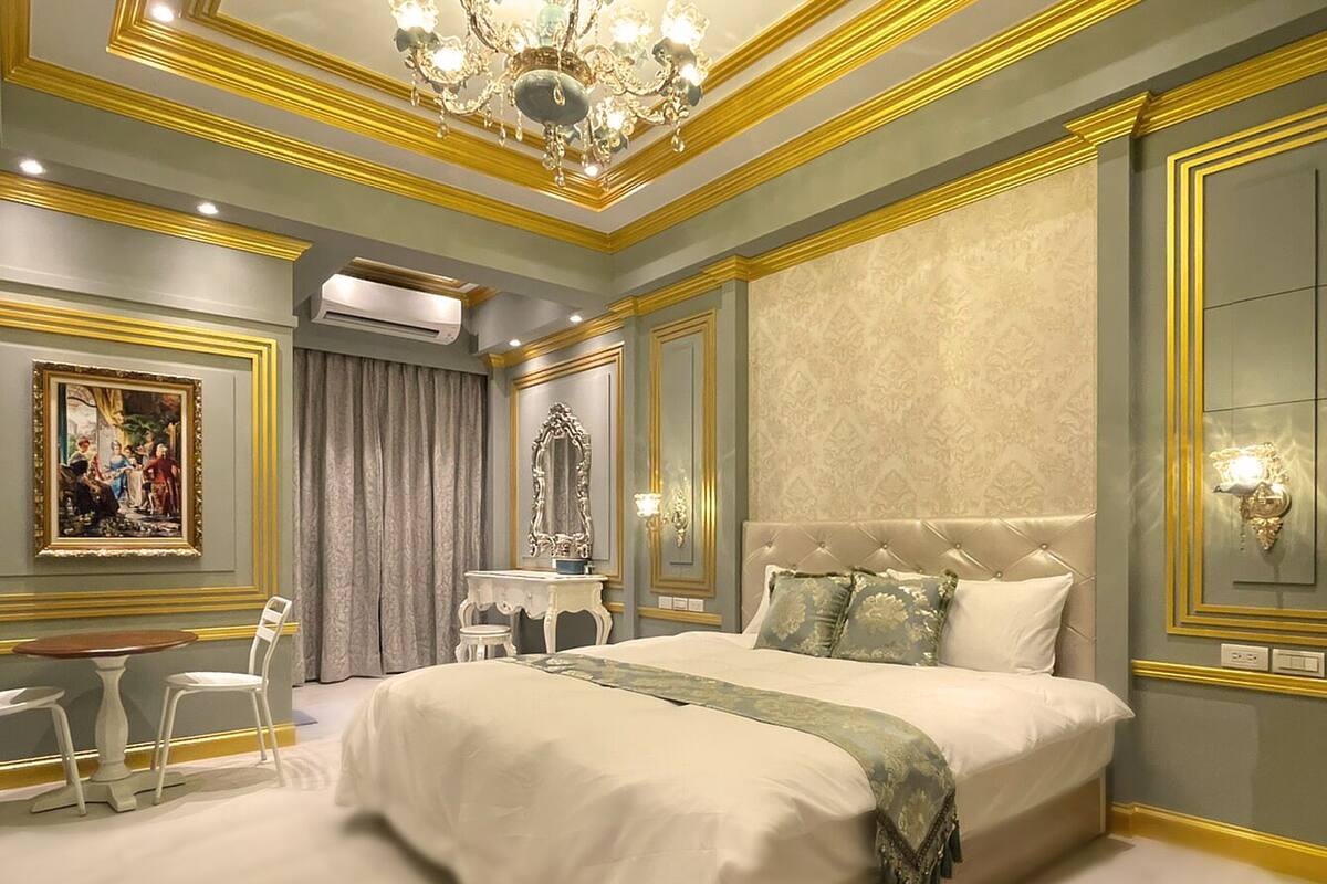 A luxurious bedroom with a large bed, a chandelier, and a classic design.
