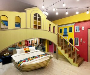 A room with a bed under a bridge-like structure, a staircase, and a view of a colorful building outside. - Time Light Walk (Hualien City)
