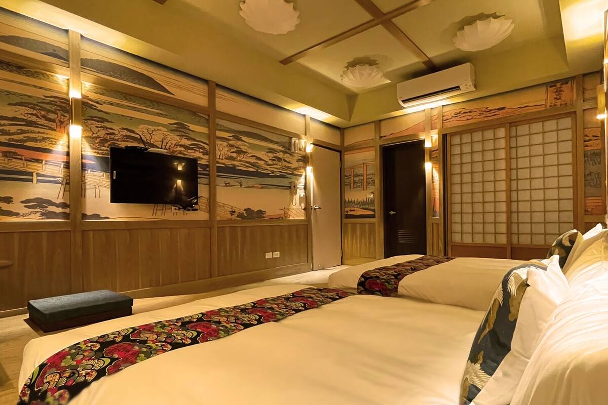 A traditional Japanese-style hotel room with tatami flooring, a television, and a sliding door.