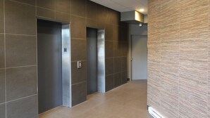 A modern hallway with two elevators and a textured wall.