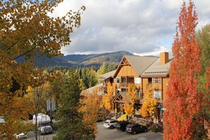 Un chalet avec une vue sur les montagnes, un espace de stationnement et un paysage aux couleurs automnales.