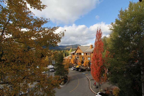 Un chalet avec une vue sur les montagnes, un espace de stationnement et un paysage aux couleurs automnales.