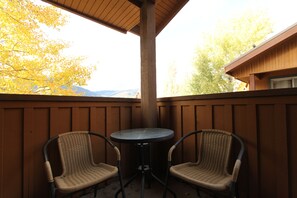 A covered patio with two wicker chairs and a small round table.