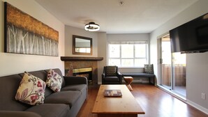 A living room with a sofa, coffee table, fireplace, and a TV.