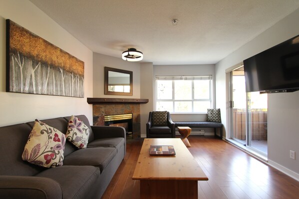 A living room with a sofa, coffee table, fireplace, and a TV.