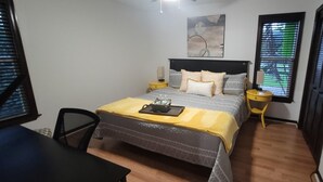 Un dormitorio con cama, mesitas de noche, un escritorio y una silla.