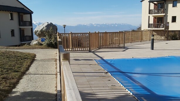 Zwembad met houten terras, uitzicht op bergen en een omheind gebied.