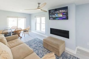Relax in this stylish living room with a large flat-screen TV, dining area, and comfortable seating.