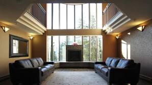 A spacious living room with a fireplace, two leather sofas, a large rug, and a stone floor.
