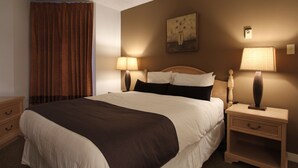 A hotel room with a large bed, two bedside tables, a nightstand, a lamp, and a painting on the wall.