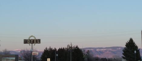 A motel with a large sign, a road in the foreground, and mountains in the background.