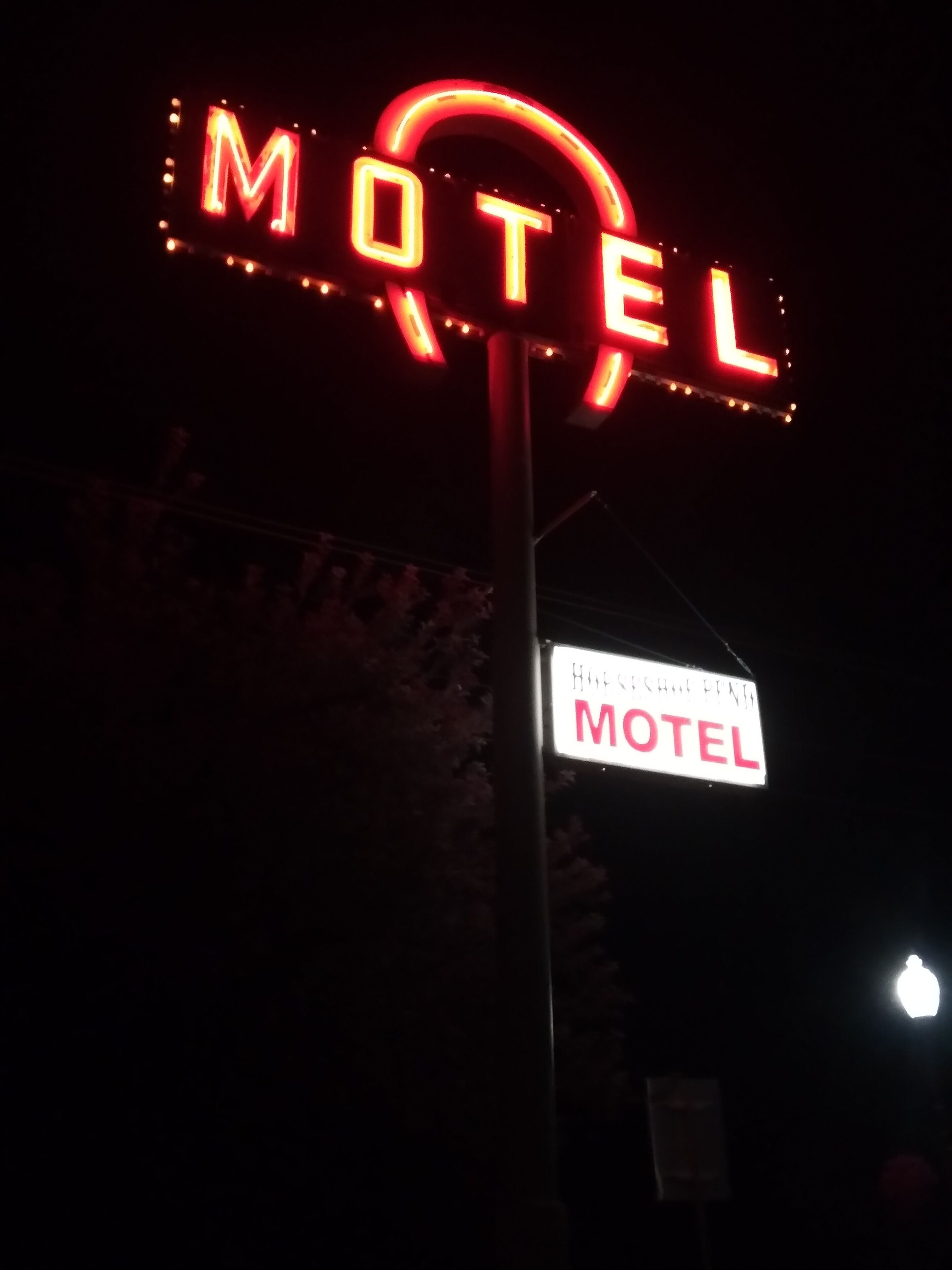 A neon motel sign with the word "MOTEL" in red letters, mounted on a pole.