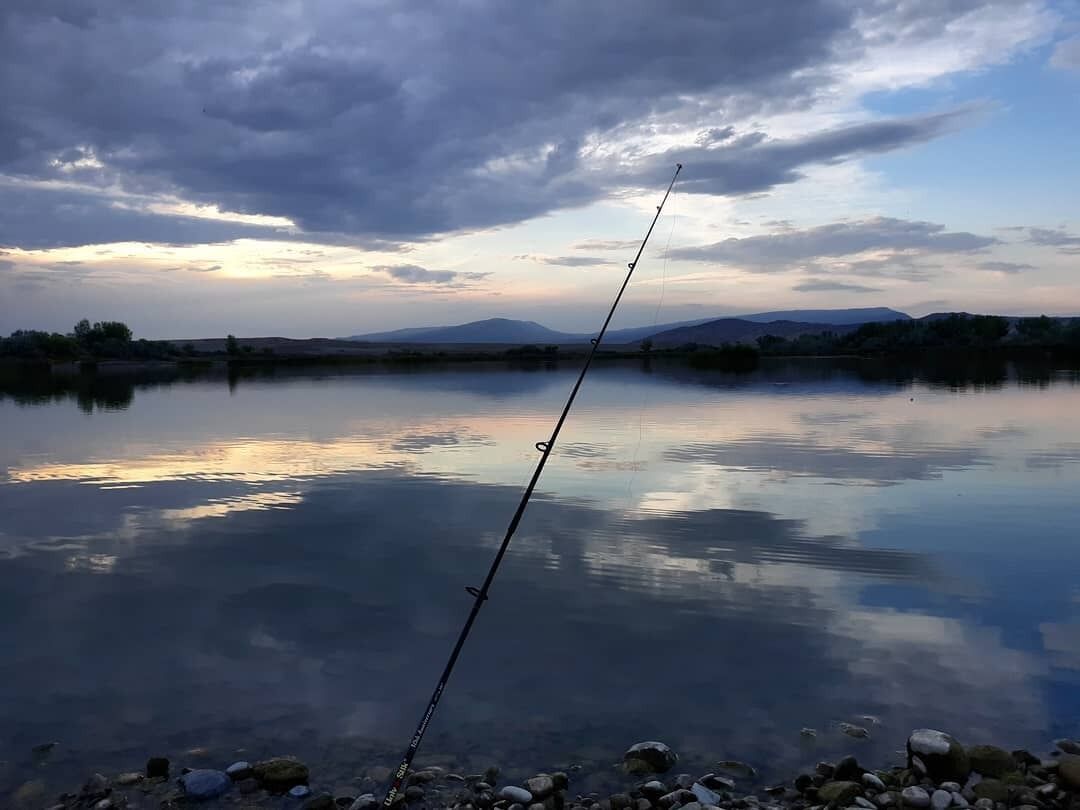 Una caña de pescar en un lago tranquilo con cielo despejado.