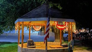 En lusthus med en grund av tegelsten, en amerikansk flagga och ljusslingor.