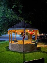 A gazebo with a brick base, an American flag, and string lights.