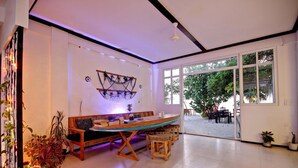 Una habitación amplia con una gran mesa de madera para comer, varias sillas y plantas en macetas.