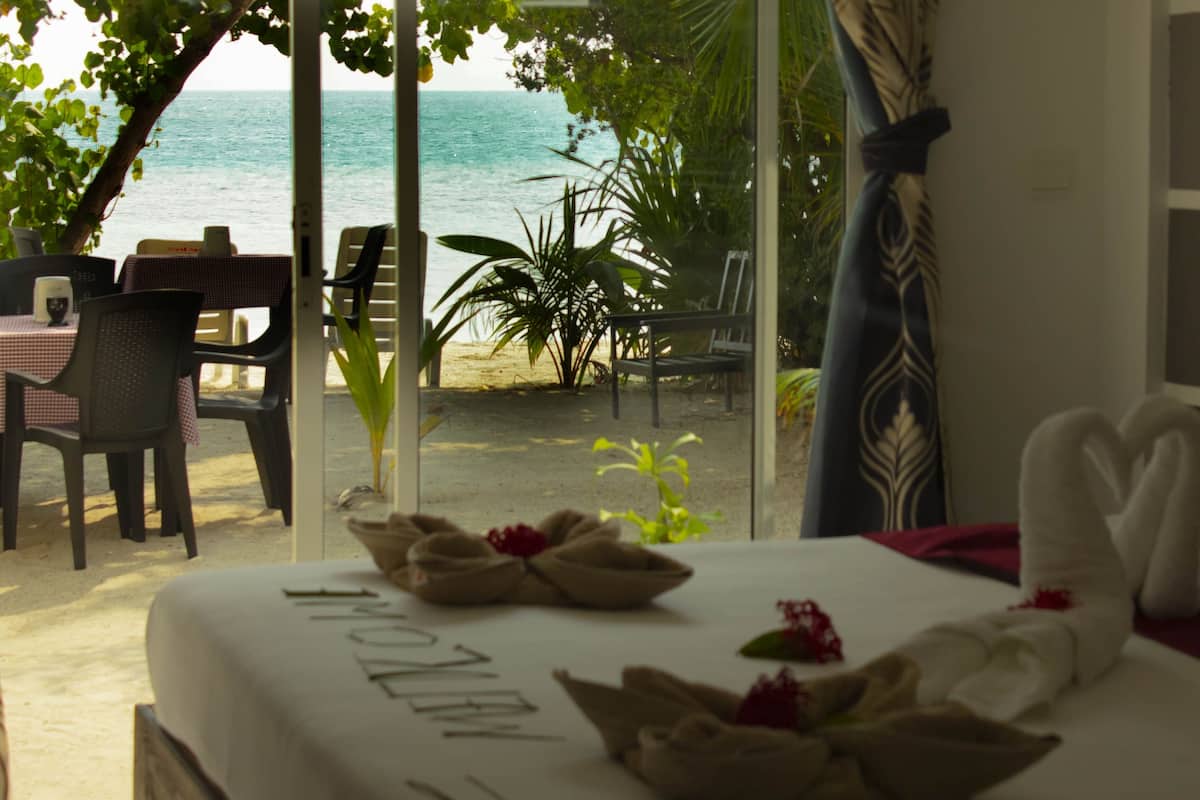 Habitación de hotel con vista a la playa, un comedor con sillas y una mesa, y una cama con toallas.