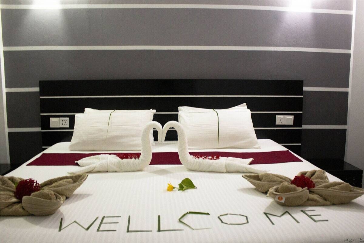 Habitación de hotel con cama, almohadas, un cisne decorativo y felpudo.