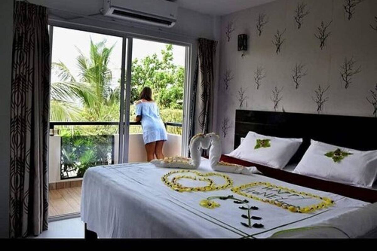 Una habitación de hotel con cama, balcón y vistas a zonas verdes.