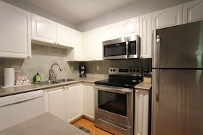 A kitchen with white cabinets, a stainless steel refrigerator, a microwave, an oven, and a dishwasher. - Sunpath #53 | 1 Bedroom Condo with Kitchen, Fireplace, and Patio (Whistler)