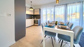 A modern kitchen with white cabinets, a built-in oven, and a dining area with a table set for four. - Moderne Ferienwohnung in Malinska mit Pool (Milcetici)