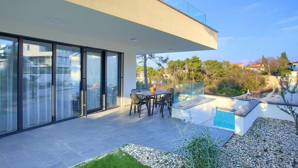 A modern house with a patio, a pool, and a view of the surrounding area. - Moderne Ferienwohnung in Malinska mit Pool (Milcetici)