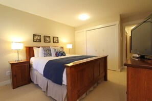 A bedroom with a bed, nightstands, a dresser, a television, and a closet.