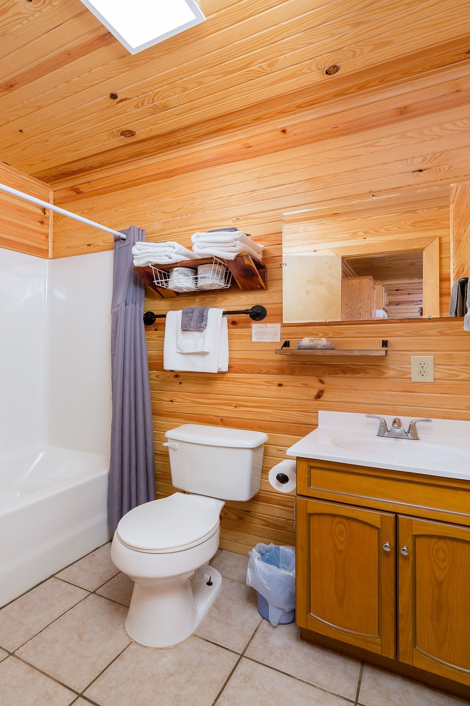 A wooden-paneled bathroom with a toilet, sink, and shower.