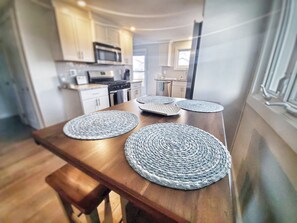 A kitchen with wooden cabinets, a microwave, and a dining table with woven placemats.