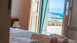 A hotel room with a bed, towels, and a view of a coastal landscape.