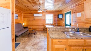 L’intérieur d’un chalet en bois comprend une cuisine, un coin repas et un canapé.