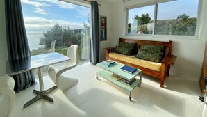 Un salon moderne avec une table en verre, un canapé en bois et une vue sur la mer.