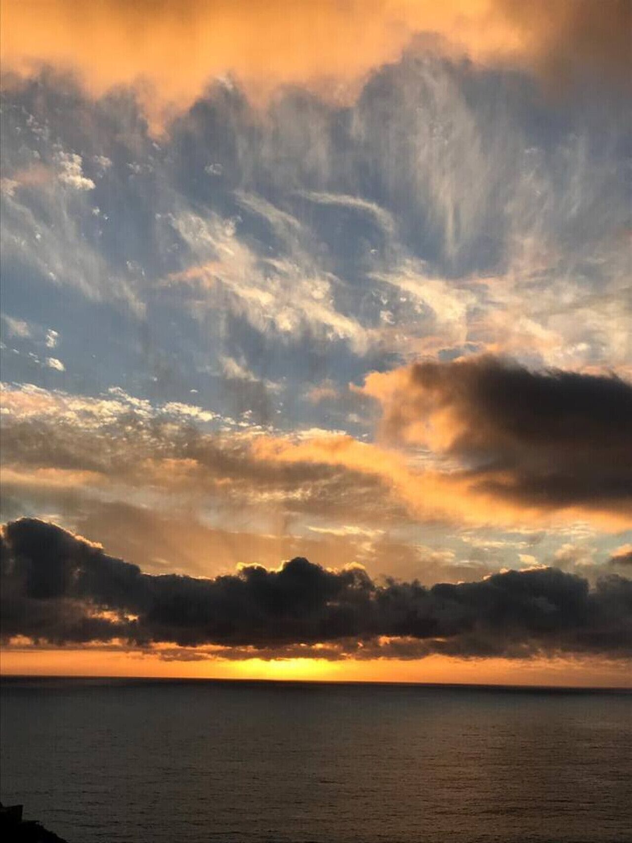 A sunset over a body of water with clouds.