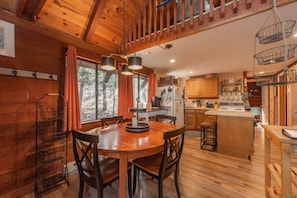 A wooden interior with a dining table, chairs, a kitchen area, and a staircase. - Chill, Play & Enjoy Nature & Memories (Swanton)