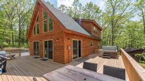 A wooden cabin with a deck, large windows, and a hot tub. - Cozy Mountain Retreat w/ Hot Tub & Fire Pit (Swanton)