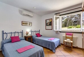 Ein Zimmer mit zwei Betten, einem Fenster mit Blick auf Bäume und einer Heizung.