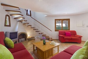 A living room with a staircase, red sofas, a TV, and a fireplace. - Gerard 4 bedroom villa, Cala Blanca (Cala Blanca)