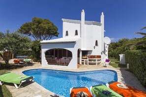 Una villa bianca con piscina, area salotto esterna e un braciere.