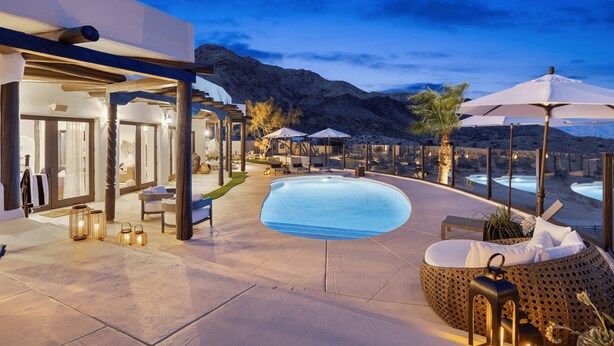 A pool area with lounge chairs, umbrellas, and a mountain backdrop.