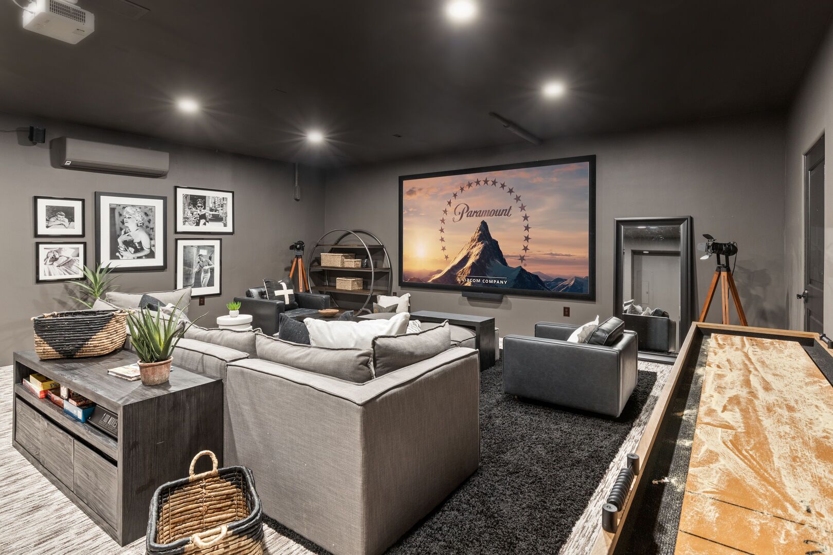 A modern home theater room with a large screen, comfortable seating, and a projector setup.