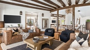 A spacious living room with wooden beams, a large mirror, and a cozy seating area with a coffee table.